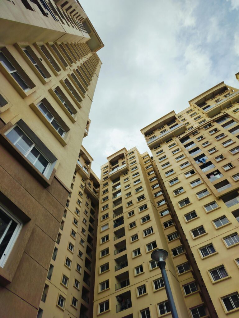 Urban cityscape showing towering apartment buildings in Bengaluru under a cloudy sky.
